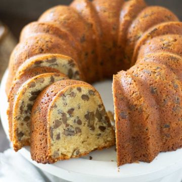 Butter pecan pound cake on a white serving plate with a few slices cut.