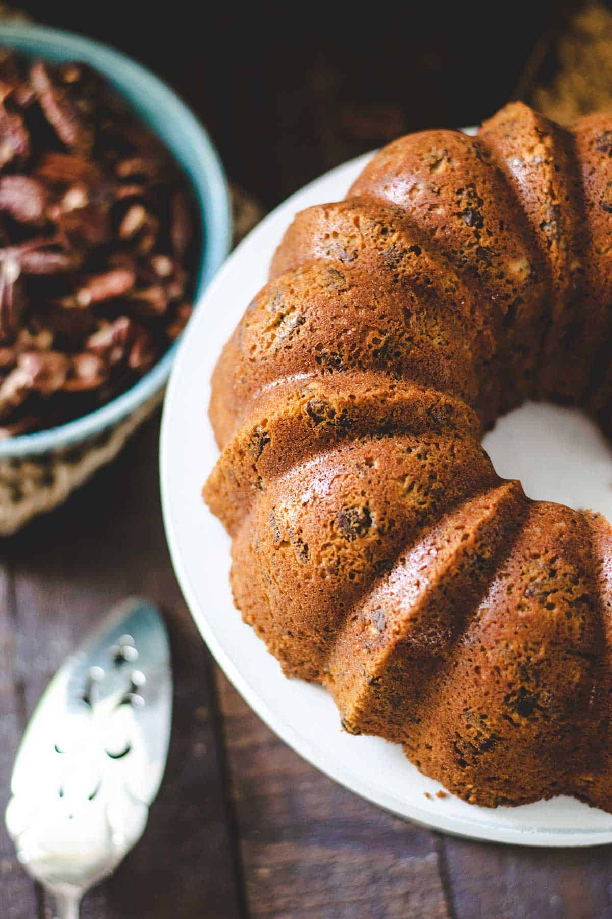 Southern Pecan Pound Cake on a wooden table with pecan in the background.