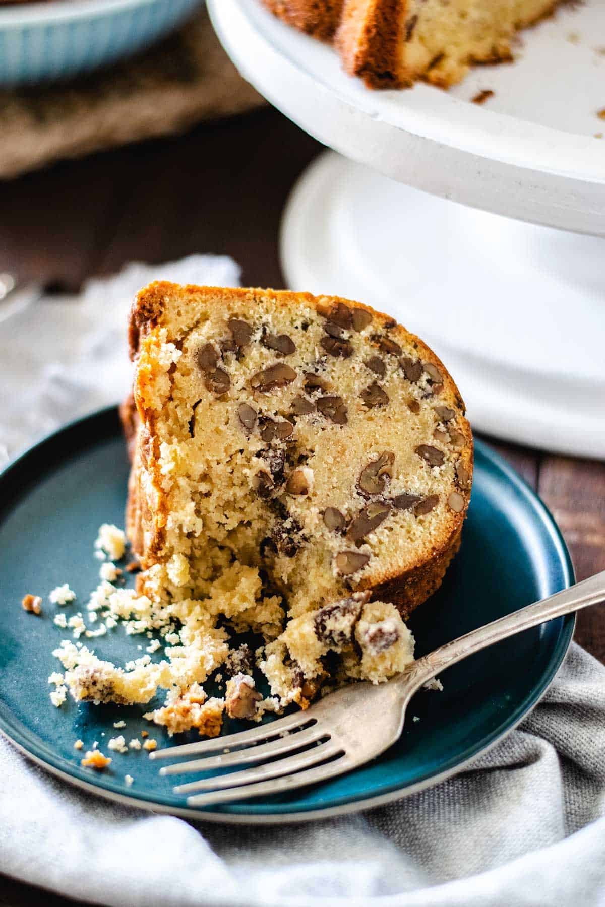 a slice of this toasted pecan pound cake on a blue plate with a fork