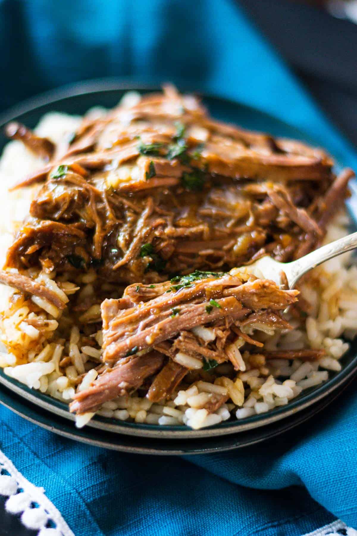 A fork full of 3-packet pot roast over a rice topped with gravy.