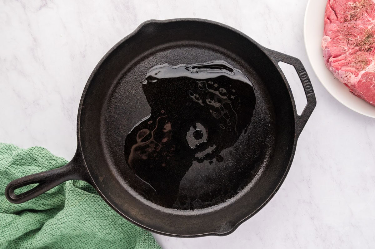 A hot cast iron skillet with avocado oil in the bottom.