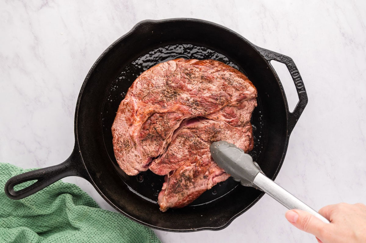 A seared chuck roast in a cast iron skillet.