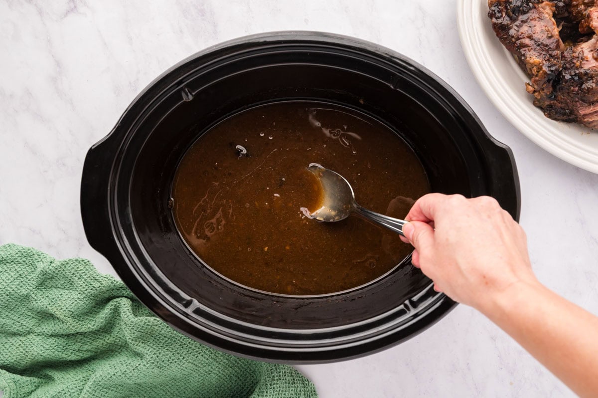 Stirring the slurring into the liquids in the slow cooker.
