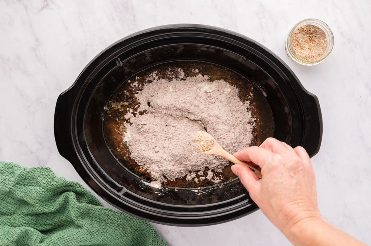 Sprinkling the dry onion soup mix on top of the chuck roast.