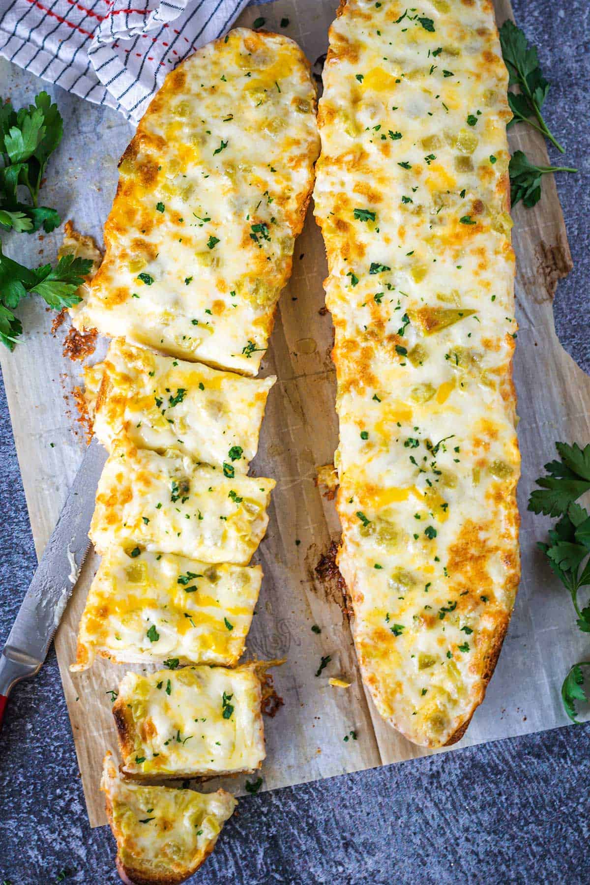 Cheesy Green Chile Bread on a parchment lined board partially sliced.