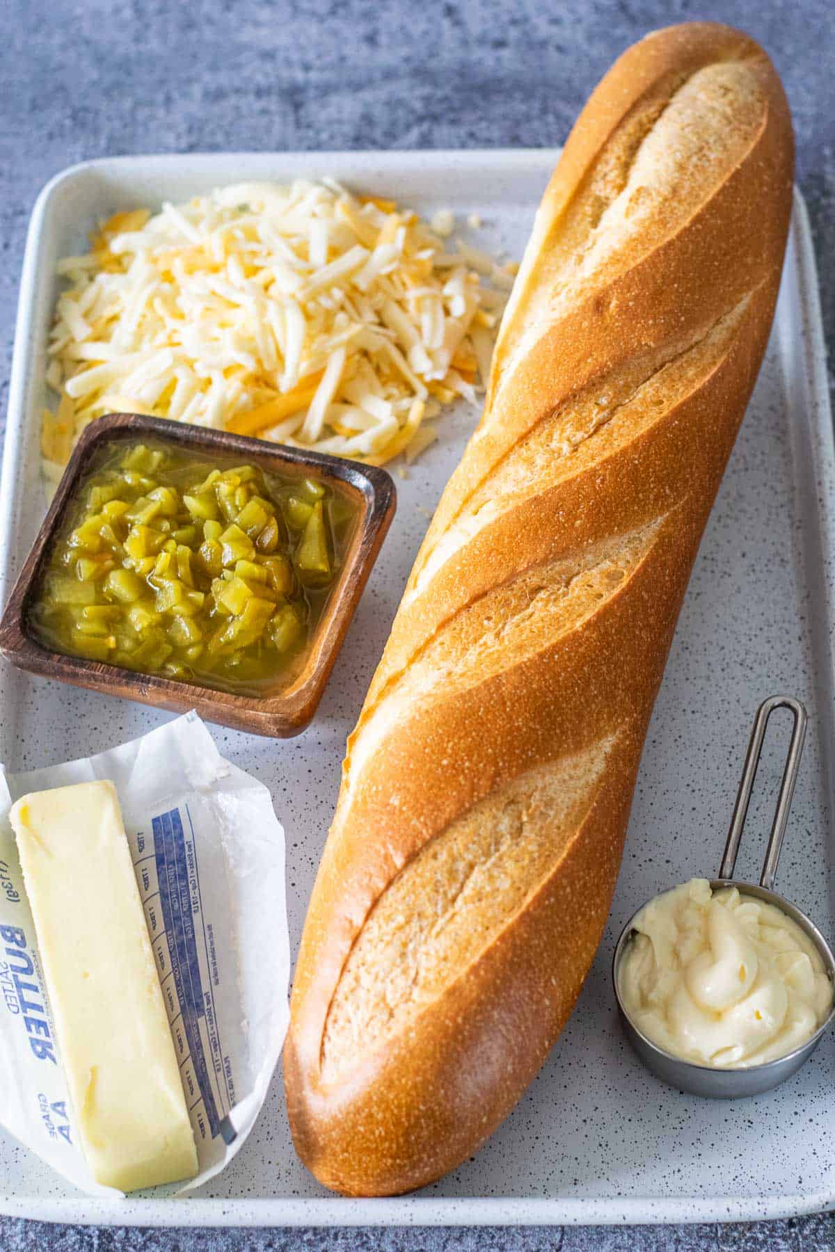 Image of ingredients used for cheesy green chile bread - french bread, butter, mayo, green chiles, and shredded cheese.