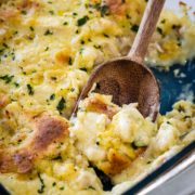 A clear casserole dish with a spoonful of dumplings being scooped out.