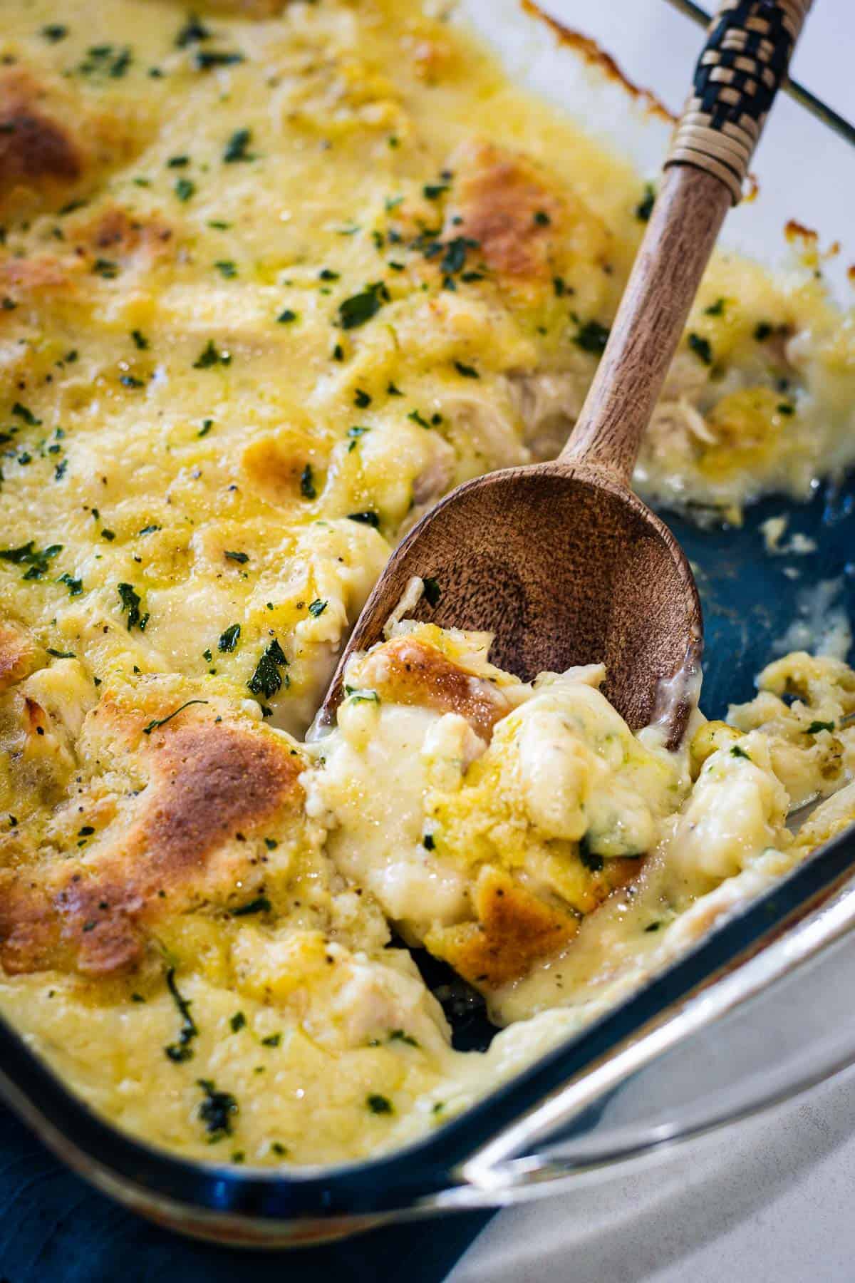 A clear casserole dish with a spoonful of dumplings being scooped out.