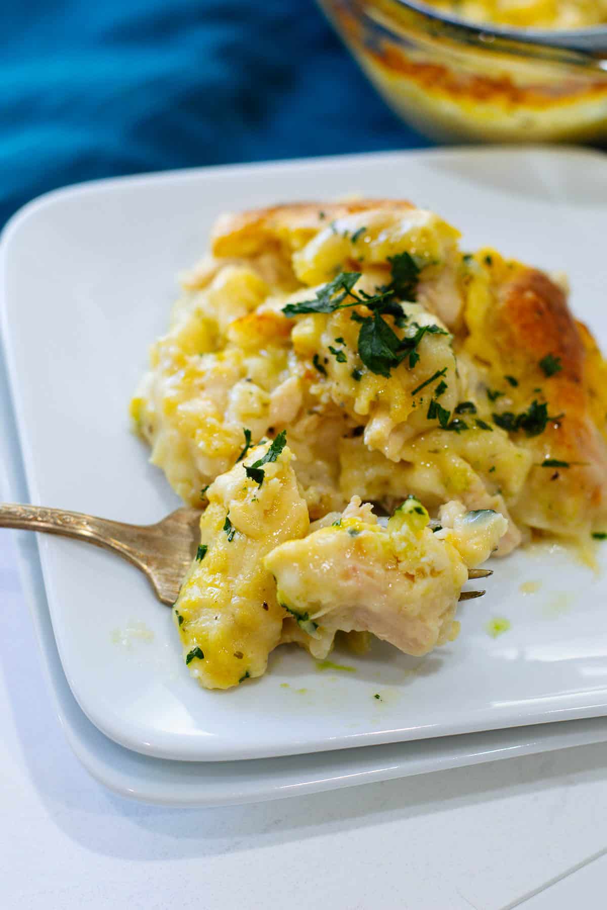 Fork full of chicken and dumplings casserole on a white plate.