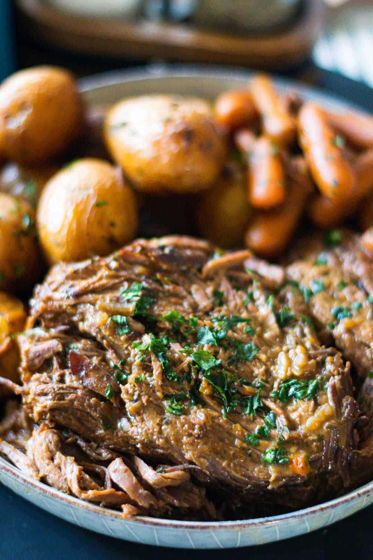 Up close image of 3-packet pot roast shredded in a serving platter with carrots and potatoes.