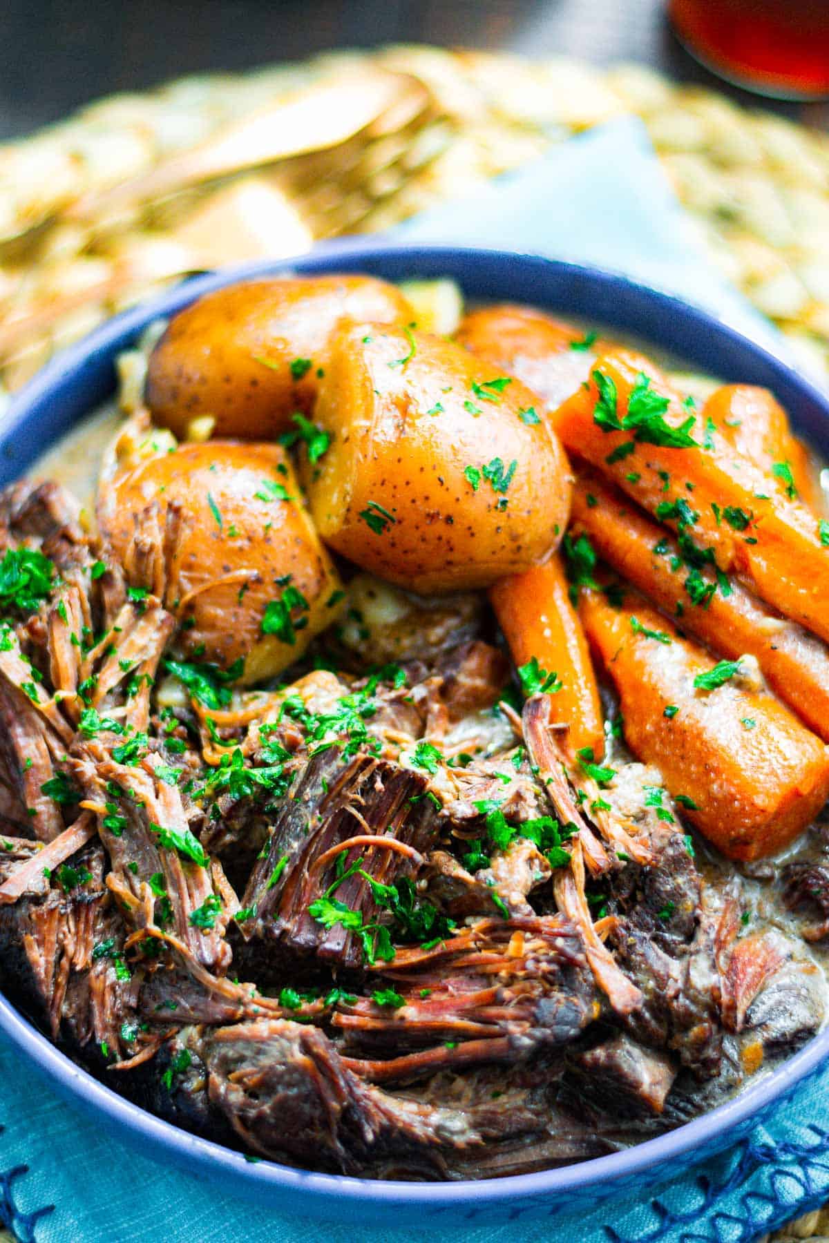 Shredded Ultimate Pot Roast in blue serving dish with potatoes and carrots.