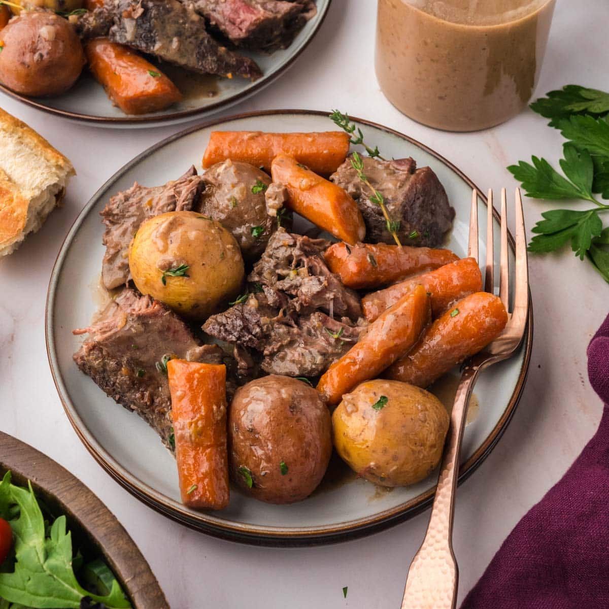 A plate of sliced pot roast, baby potatoes, and carrots.