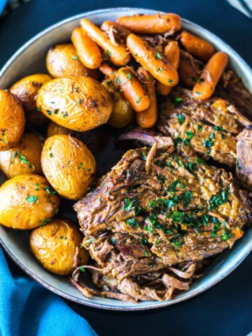 Overhead image of 3-packet pot roast on a serving bowl with carrots and potatoes.