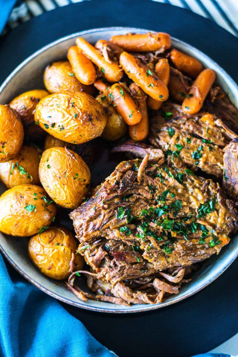 Overhead image of 3-packet pot roast on a serving bowl with carrots and potatoes.