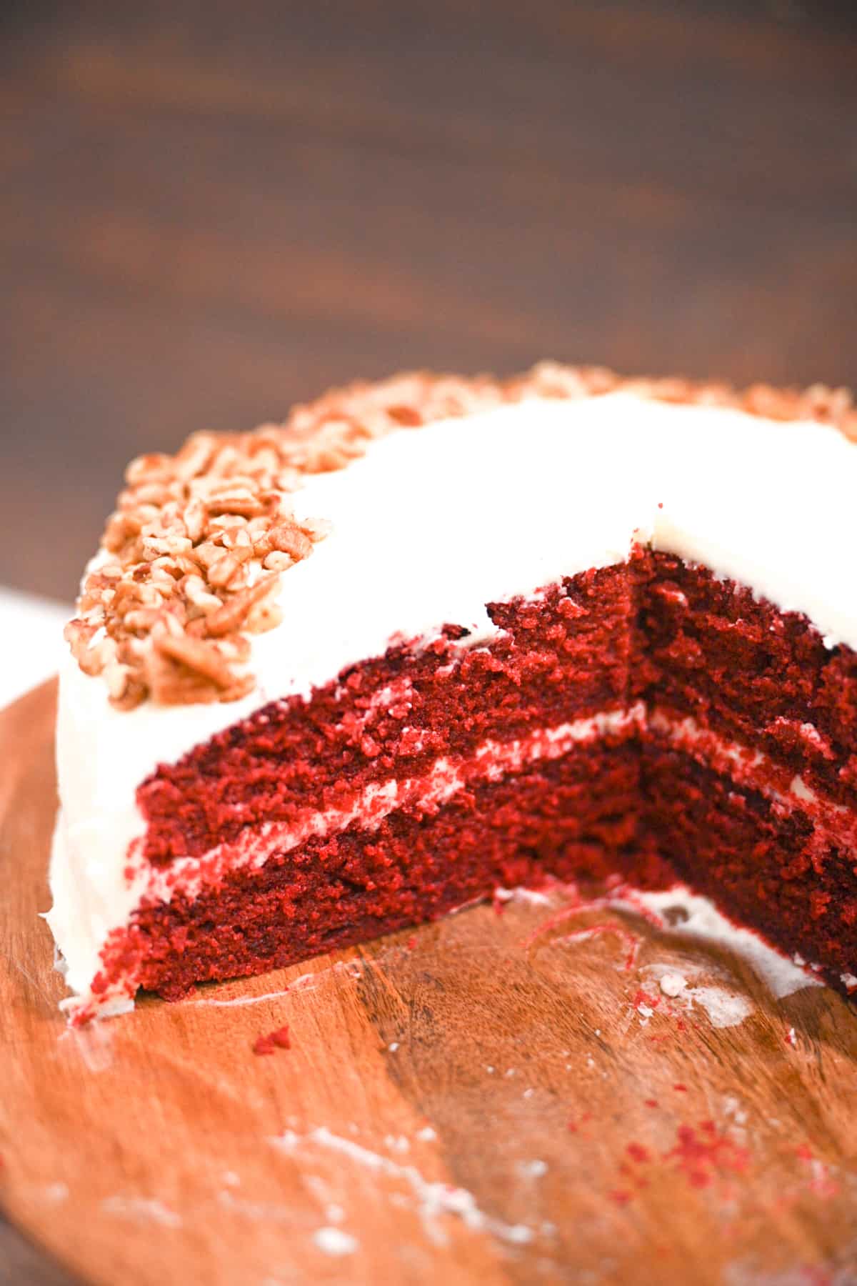 Image of whole red velvet cake partially sliced.