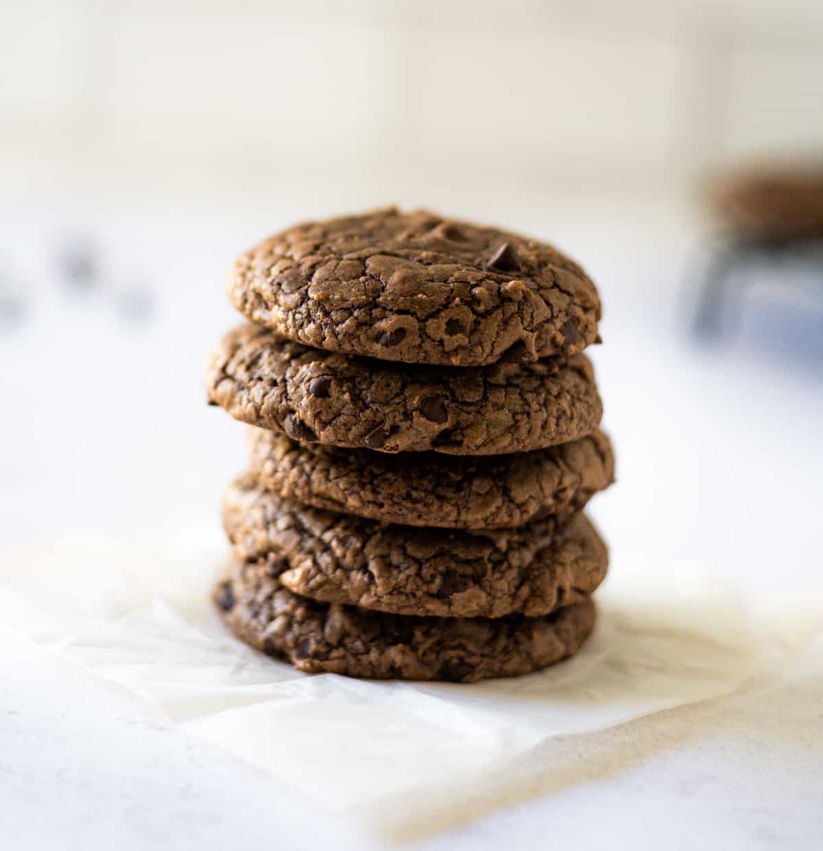 Stacked brownie mix cookies on white parchment paper.