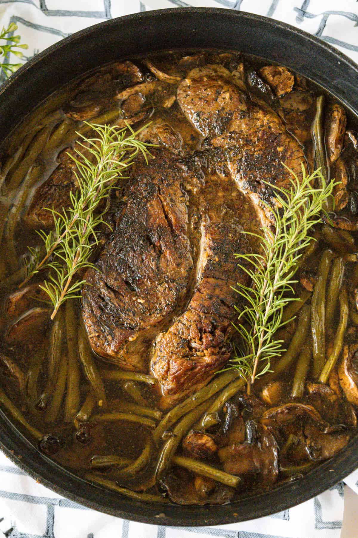 Pot Roast in a cast iron dutch oven garnished with rosemary.