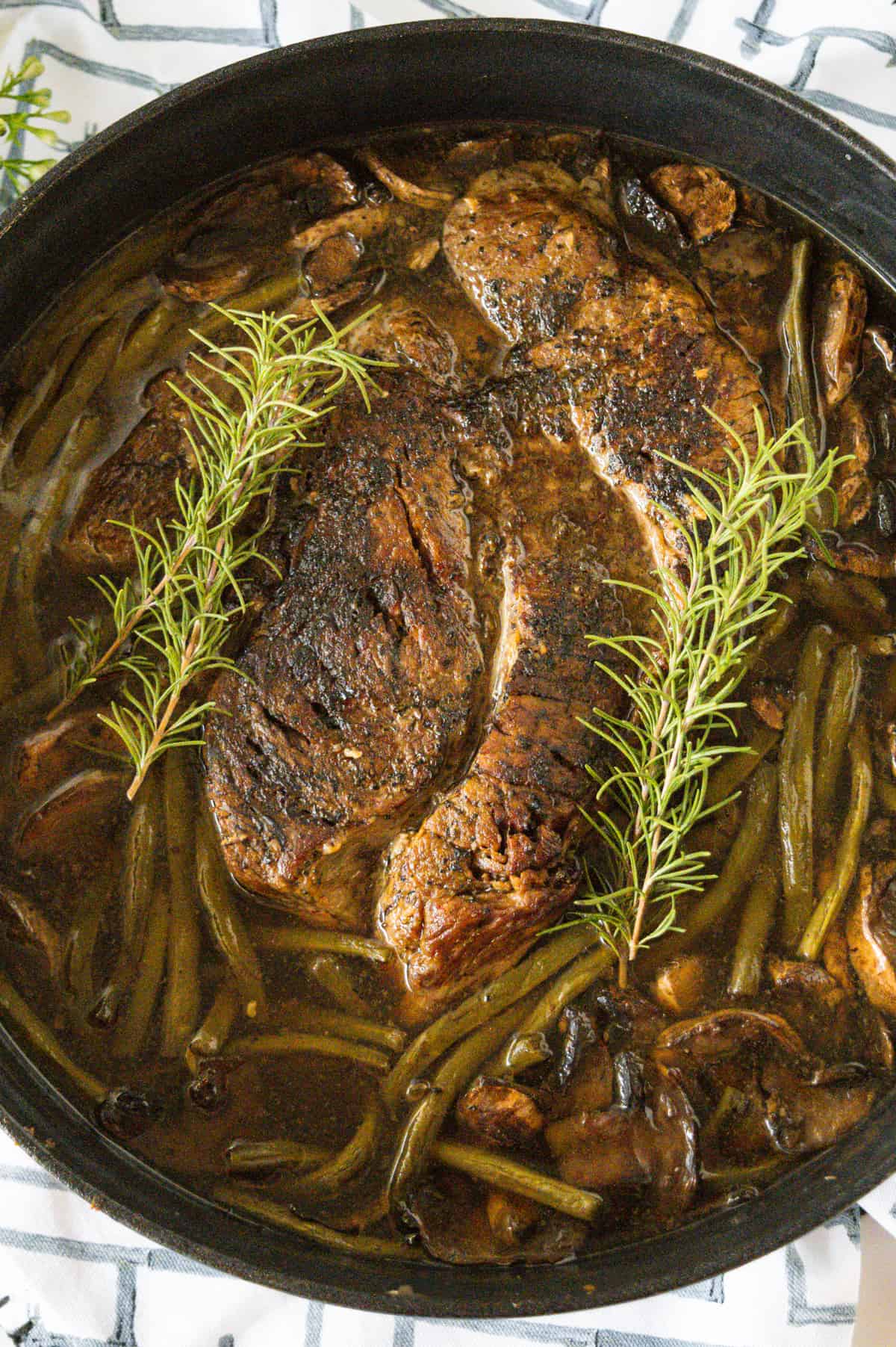 Pot Roast in a cast iron dutch oven garnished with rosemary.