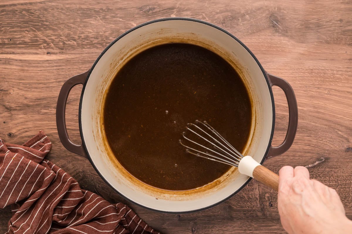 Whisking gravy to desired thickness in dutch oven.