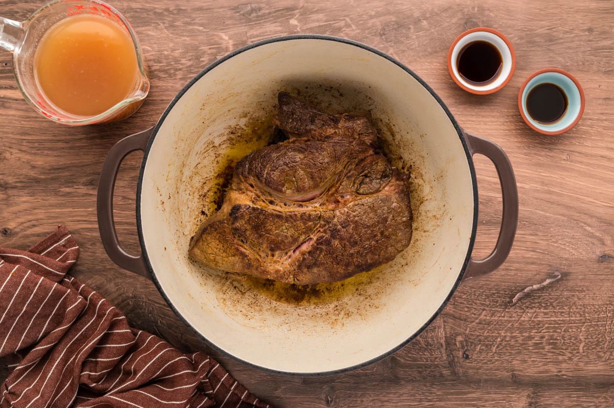 A seared chuck roast in a dutch oven.