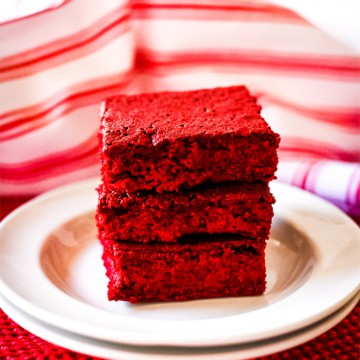 Stacked sliced red velvet brownies on a white plate.