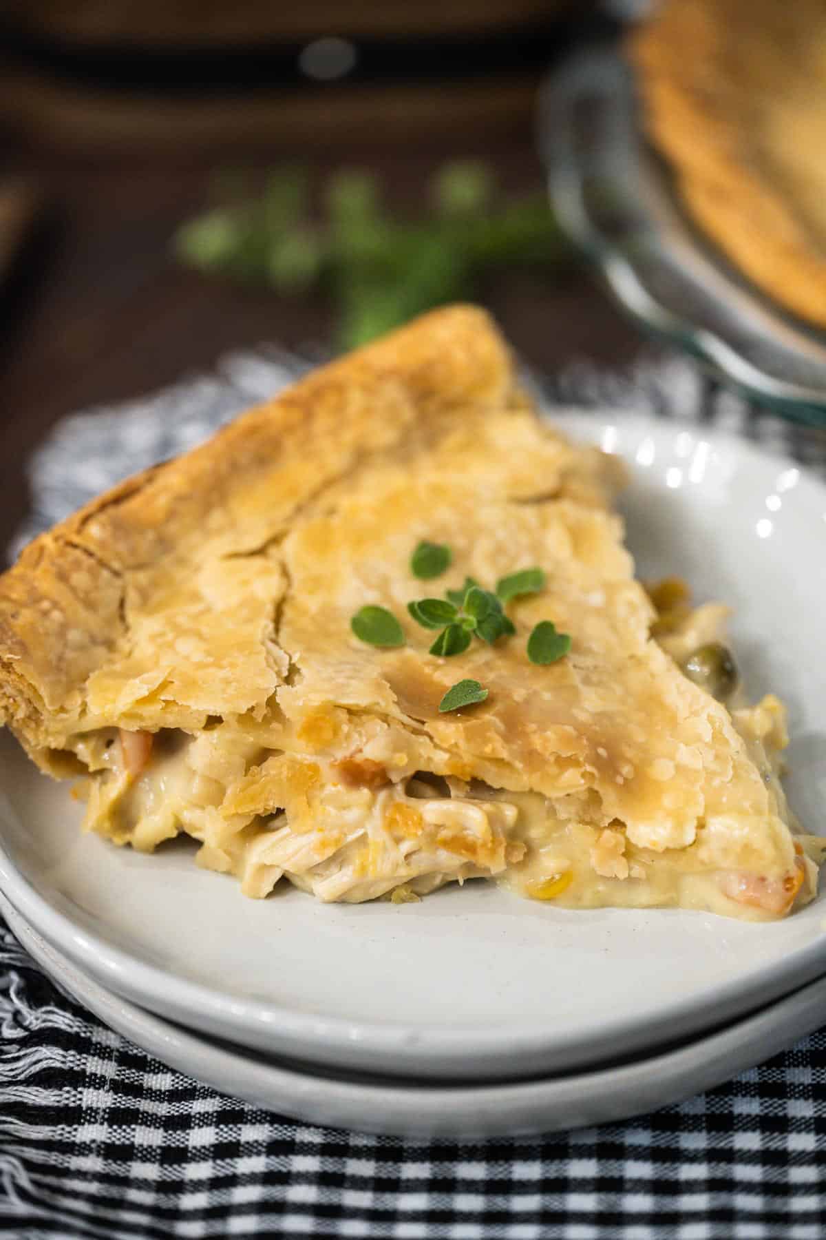 An upclose image of a flaky chicken pot pie with fresh thyme sprinkled on top.