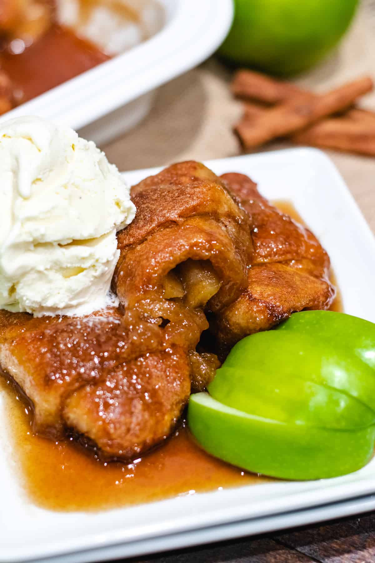 An upclose image of a plate full of easy apple dumplings with ice cream on top.