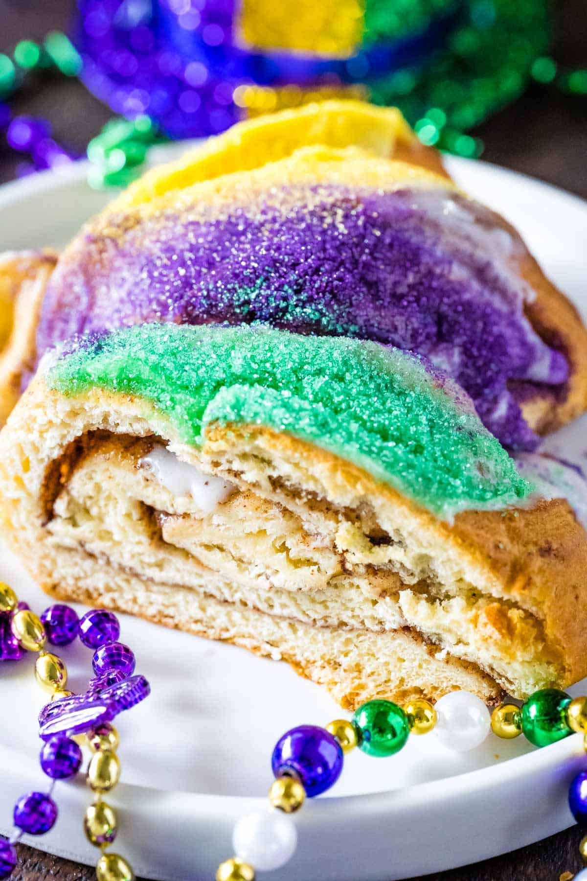 Upclose image of a king cake slice showing layers of cinnamon and icing drizzled over the cake.