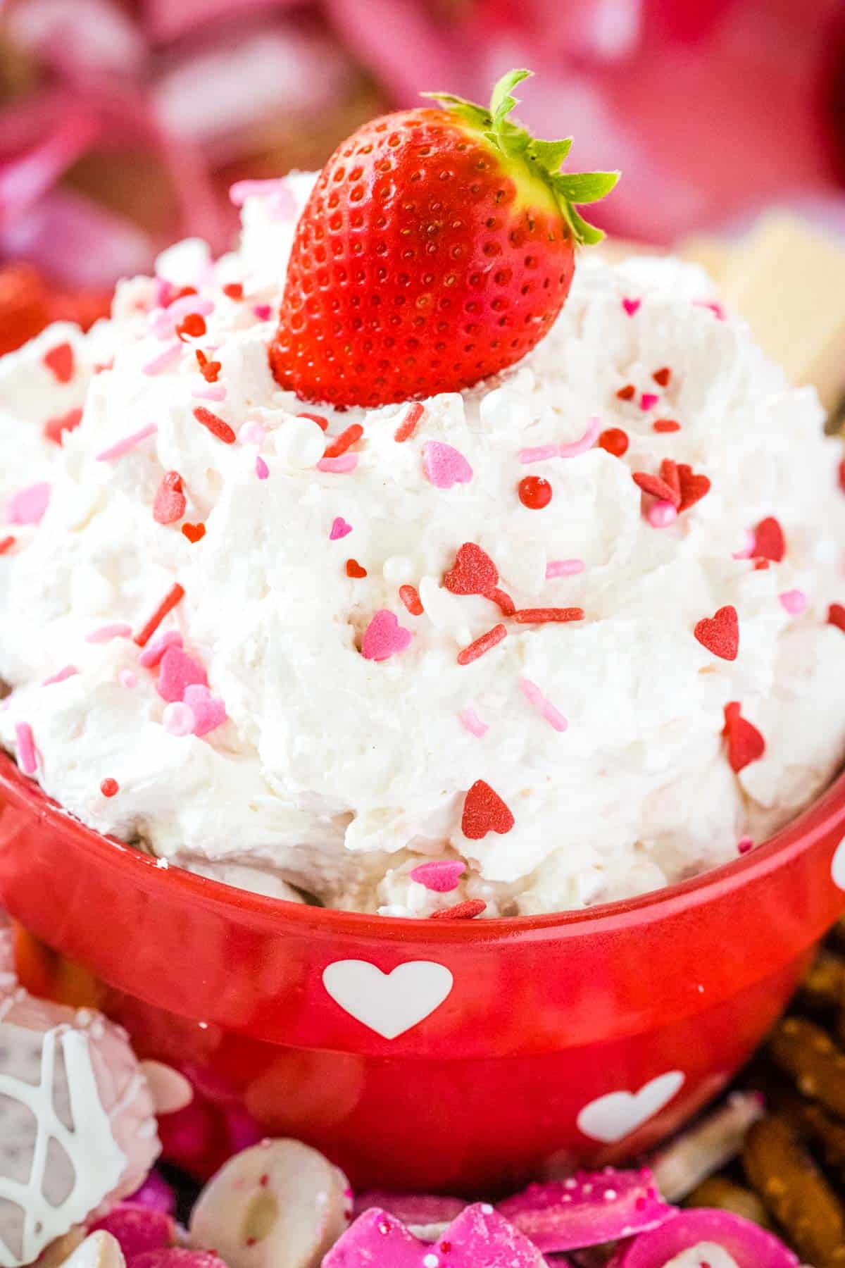 Upclose image with a red heart shaped bowl filled with heart snack cake Valentine's Day dip.