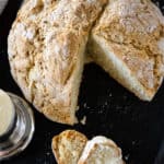 Up close overhead image of a sliced soda bread a black tray with crumbs scattered about.