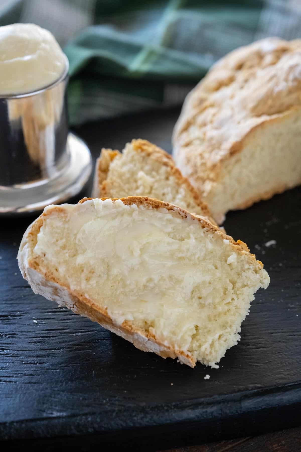 An upclose image of a slice of soda bread slathered in butter.