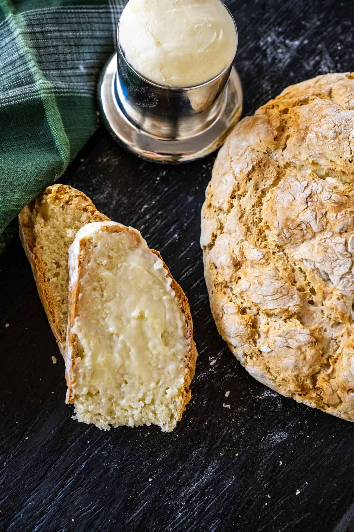 Irish soda bread sliced and buttered set beside a loaf.