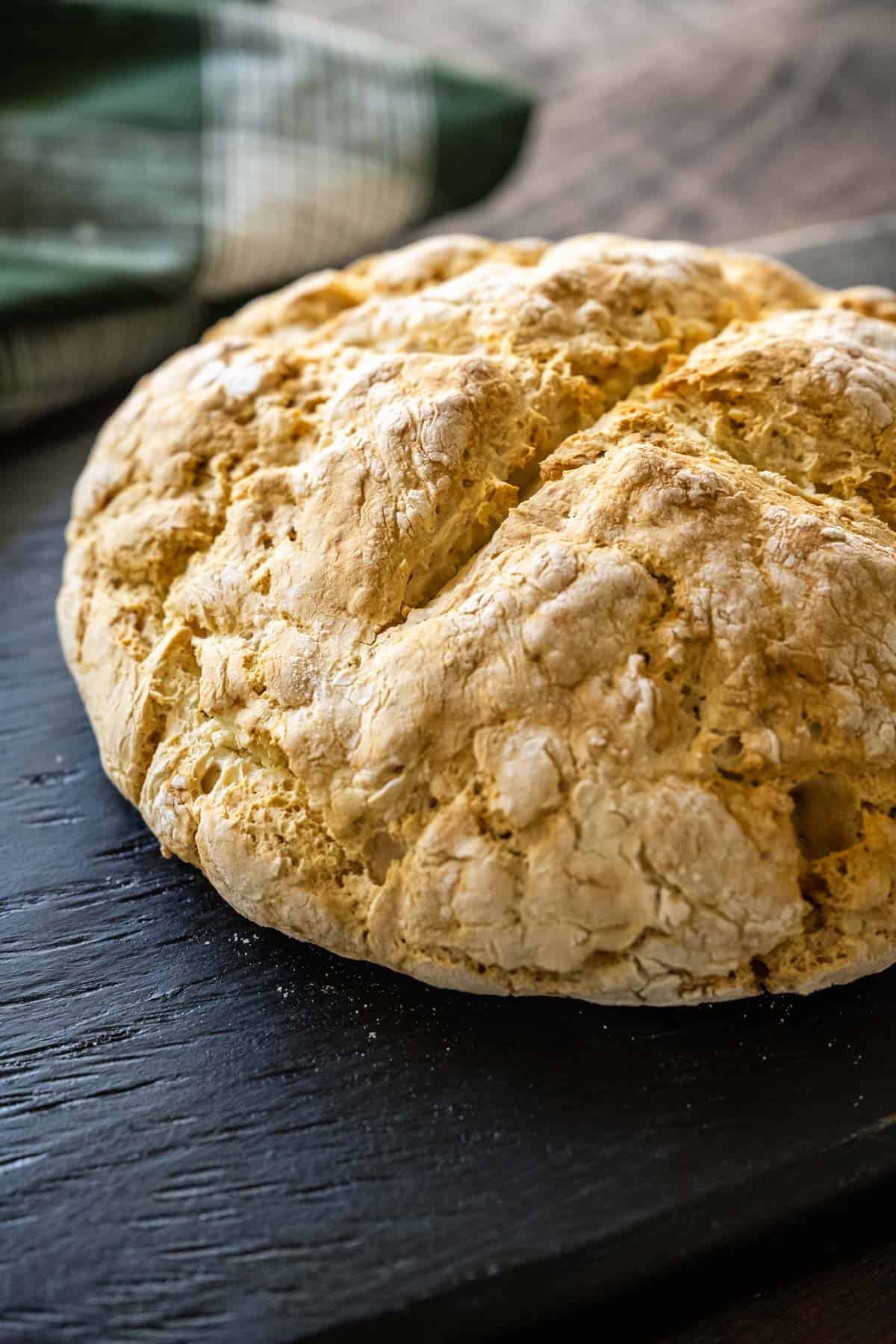 A loaf of Irish soda bread on a black serving board.