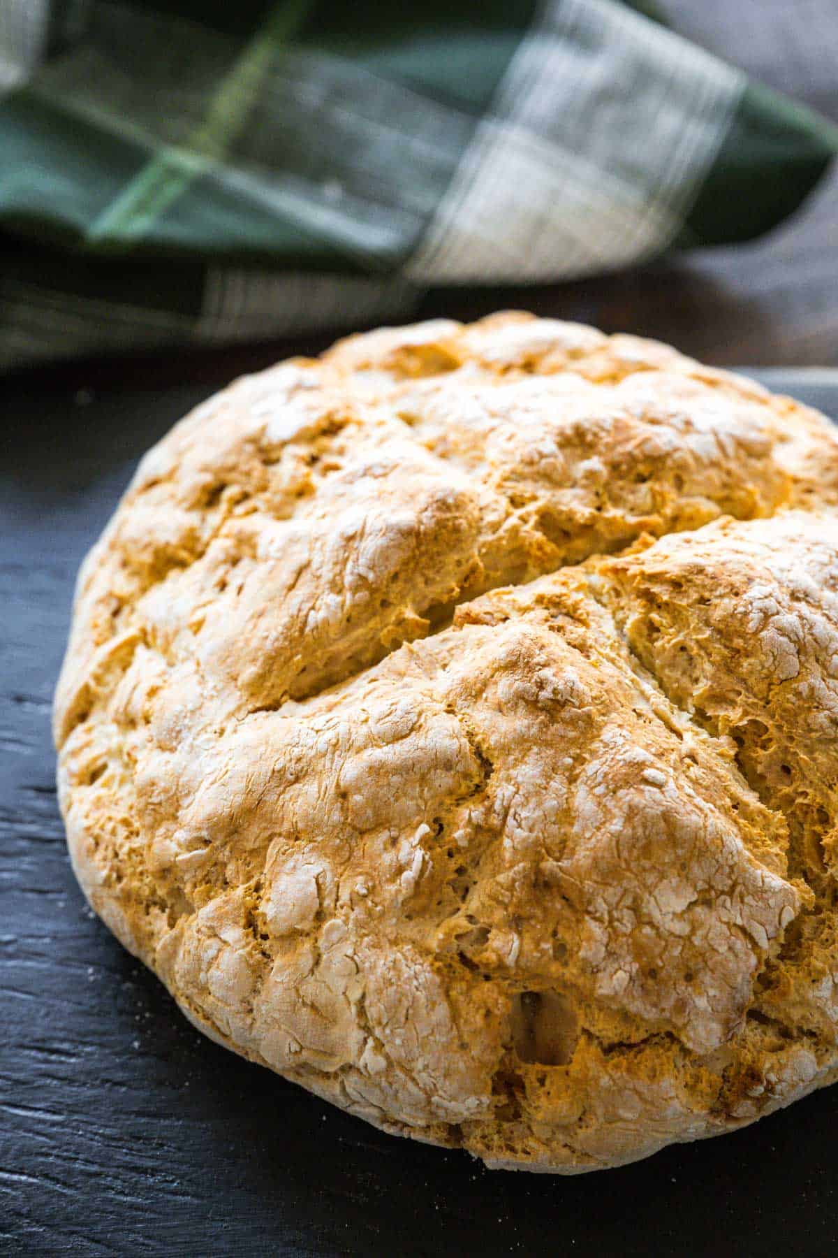 Upclose image of a loaf of soda bread highlighting all the cracks and crevices on the top of the loaf.