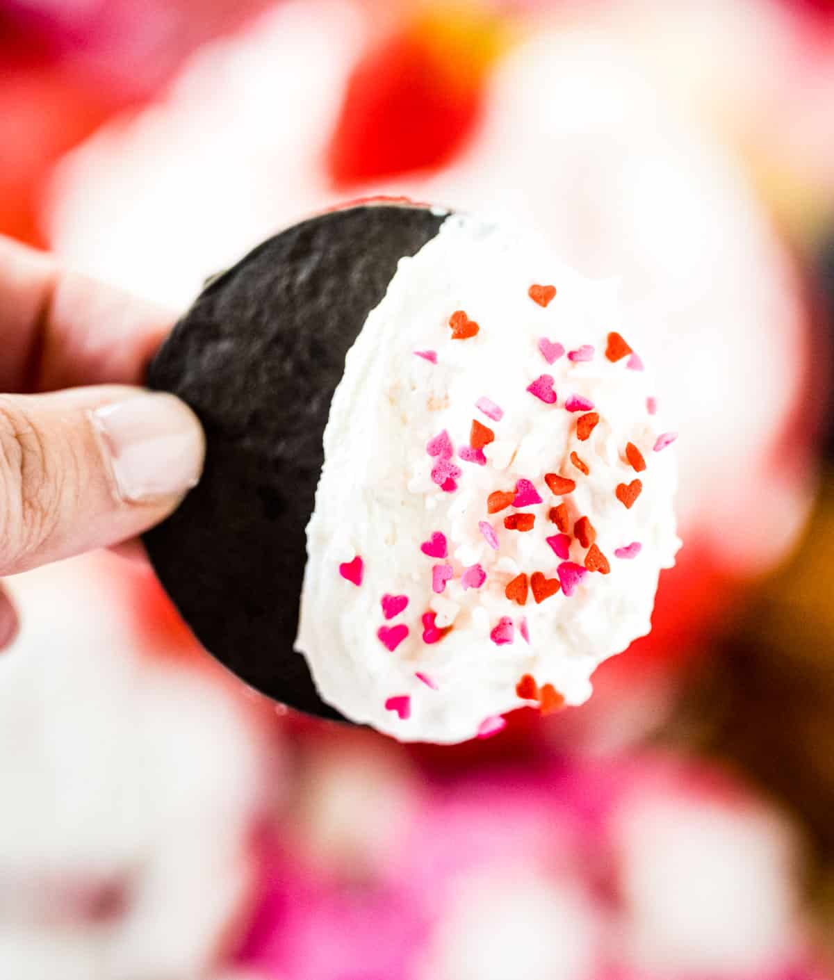 A chocolate cookie dipped in fluffy cheesecake dip with Valentine's sprinkles.