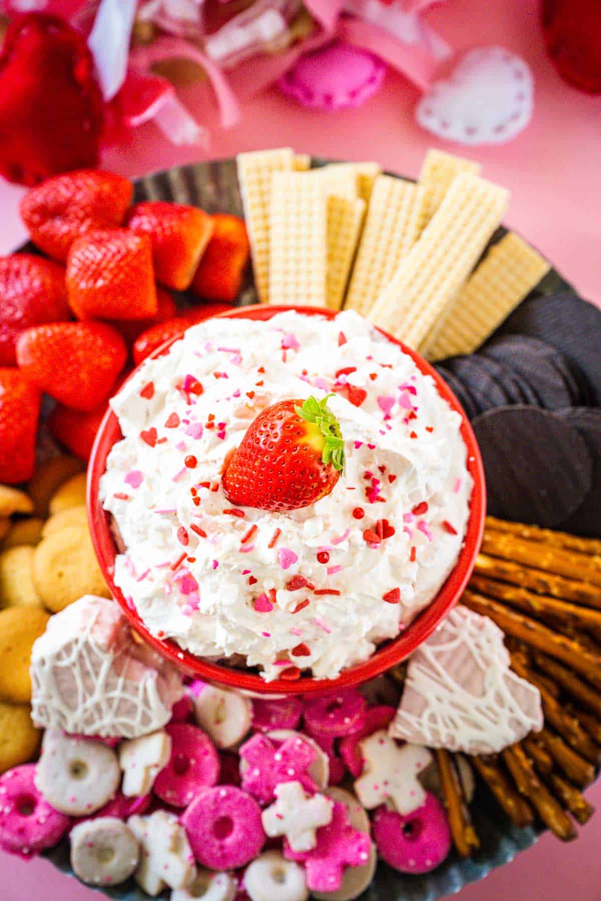 A tray filled with various cookies, pretzels, and strawberries with a heart shaped snack cake Valentine's Day Dip in the center.