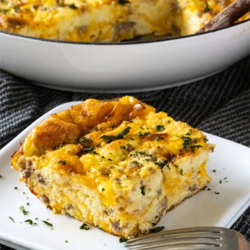 Slice of overnight breakfast casserole topped with chopped parsley.