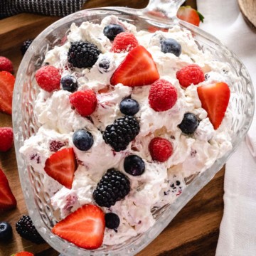 Up close image of berry cheesecake salad recipe in a glass bowl garnished with fresh berries.