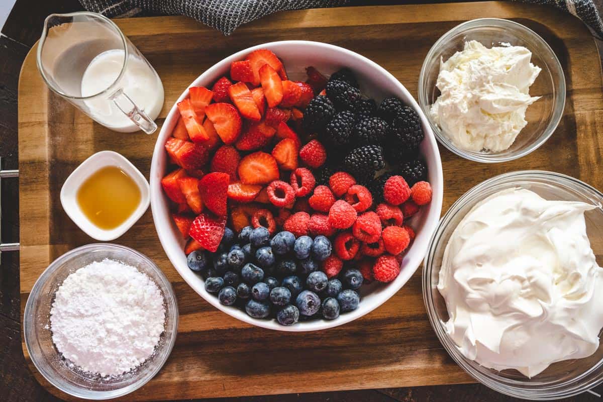 Image of ingredients needed for berry cheesecake salad recipe - Summer berries, cream cheese, cool whip. heavy cream, powdered sugar, and vanilla extract.