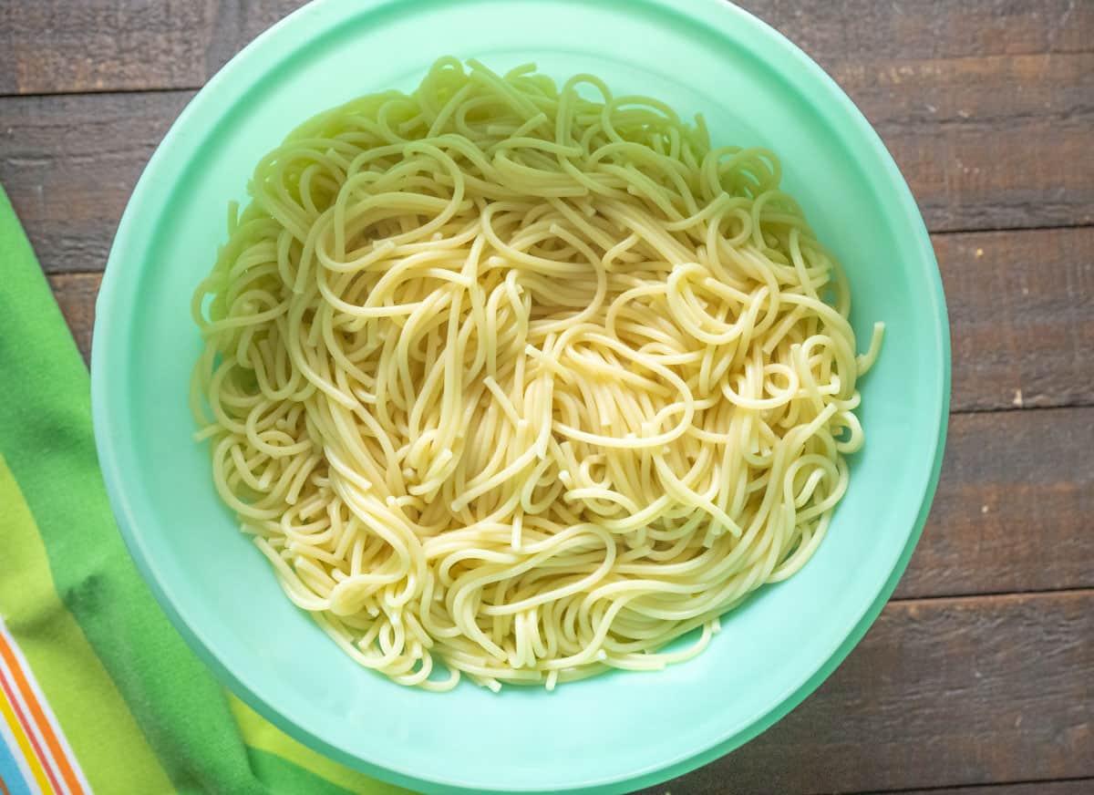 Cooked Spaghetti Noodles in a green colander.