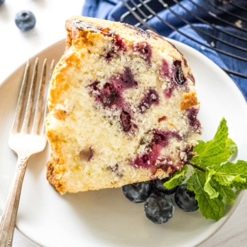 Up-close image of a slice of blueberry pound cake garnished with fresh blueberries and mint.