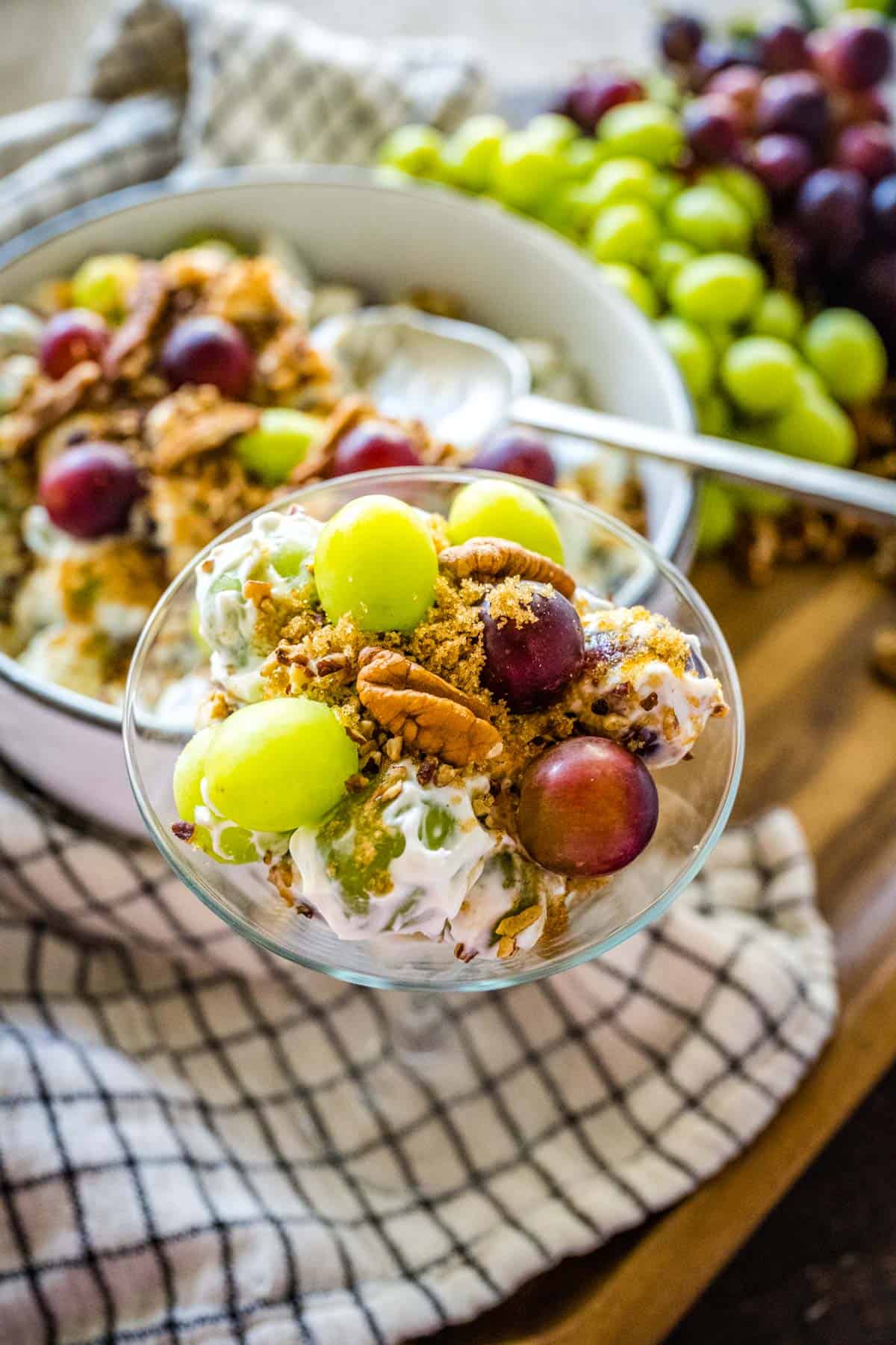 Grape salad served in a martini glass with the serving bowl in the background.