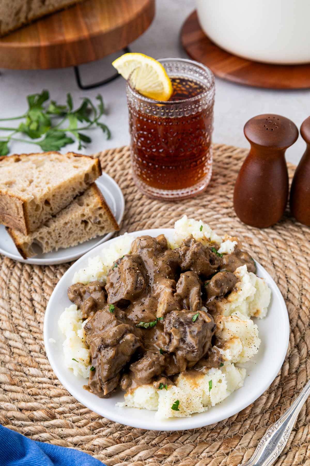 Beef tips, and gravy over mashed potatoes in a white dinner bowl.