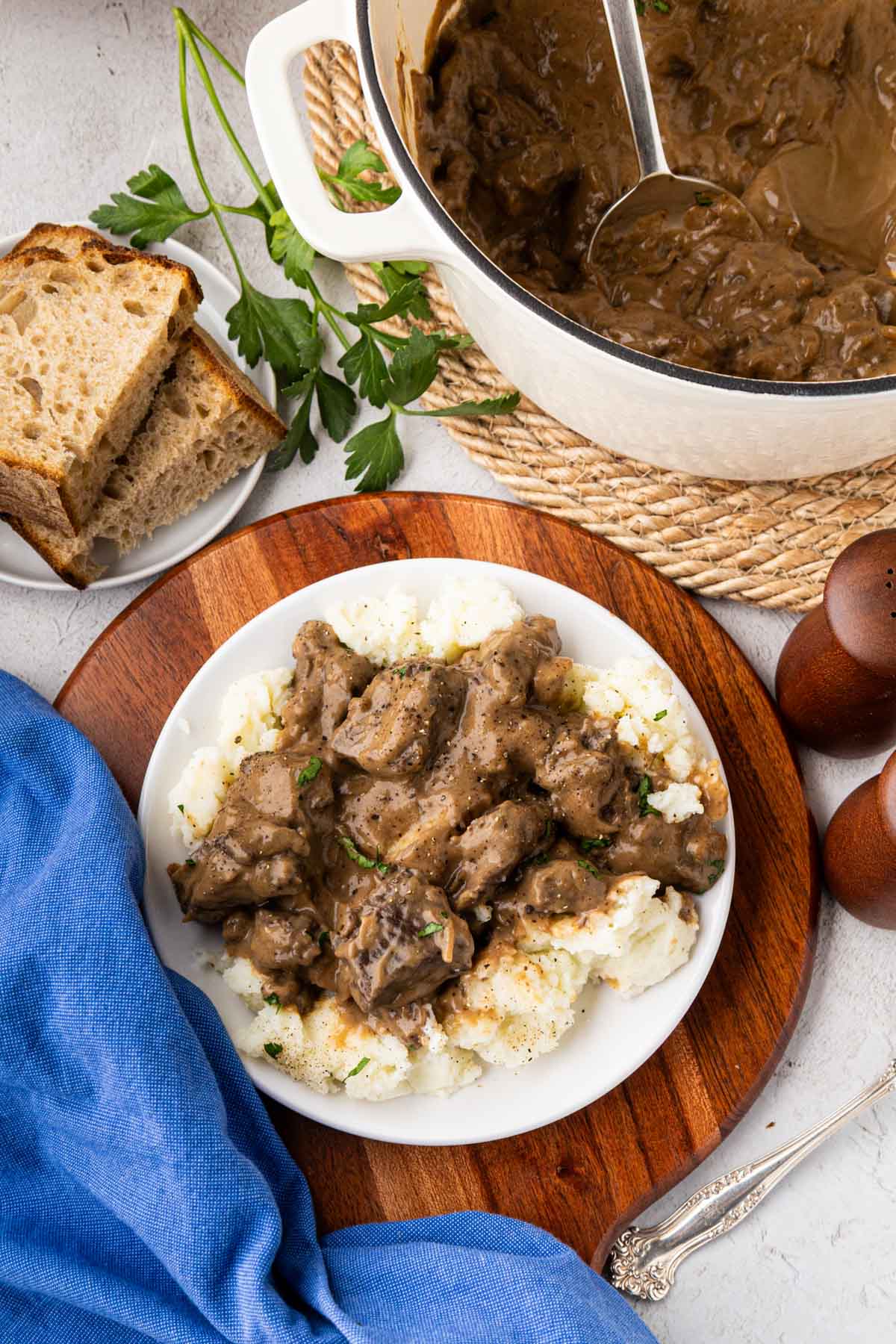 Beef tips with mashed potatoes on a serving plate with the dutch oven in the background.