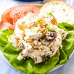 A scoop of the best chicken salad with grapes and pecans on a bed of lettuce.