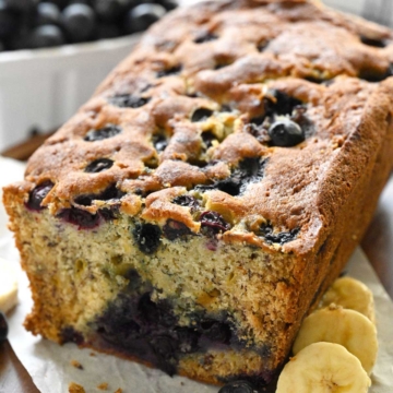 A half cut loaf of blueberry banana bread.