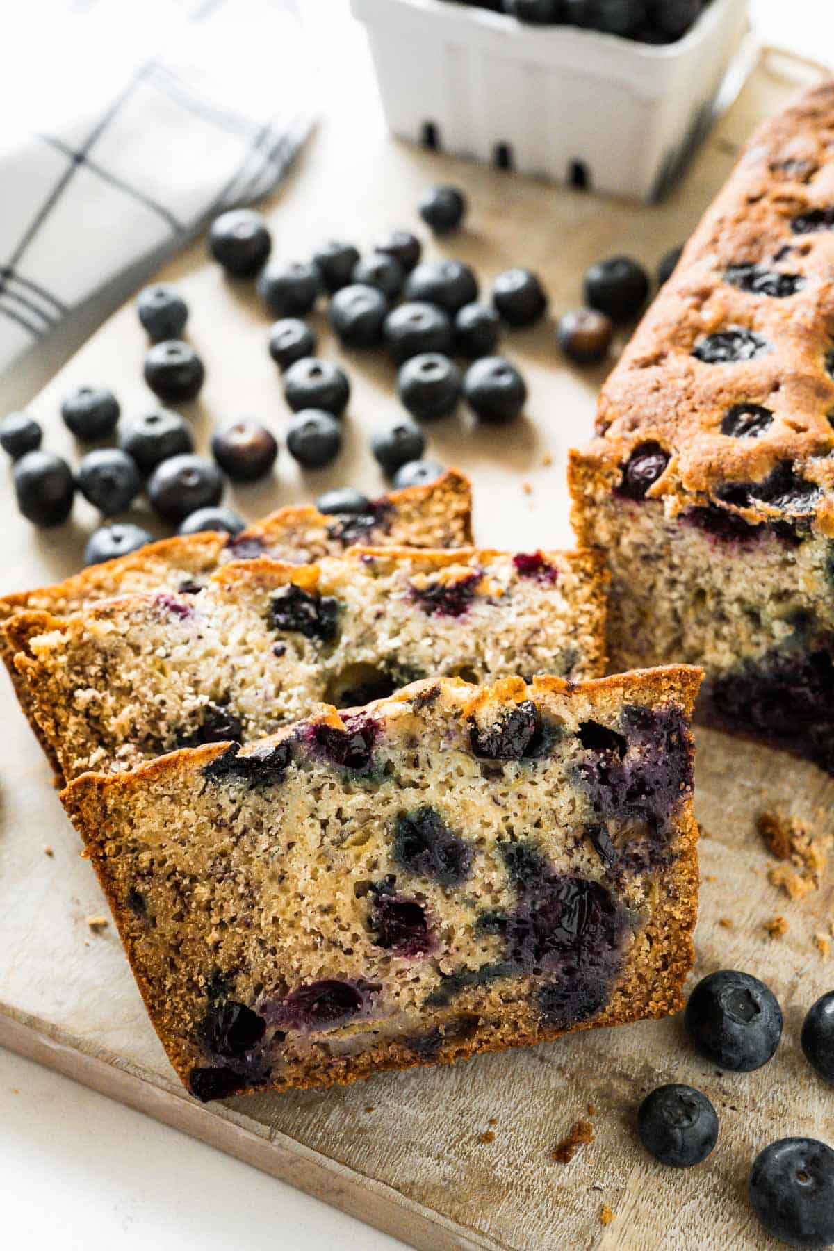 Two slices of banana bread on a wooden board beside the cut loaf.