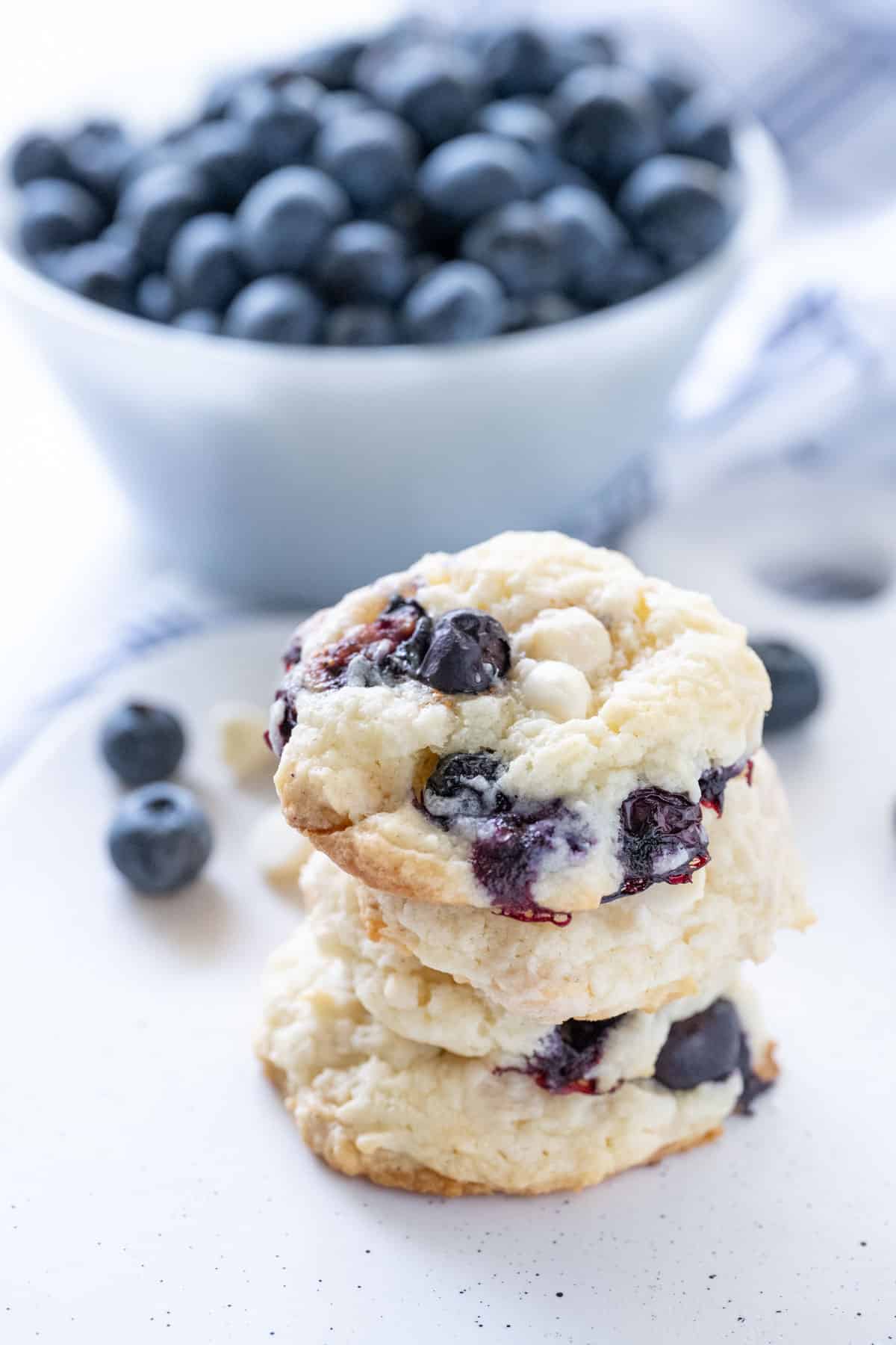 Blueberry Cookies on a speckled tray with a bowl of fresh blueberries in the background.