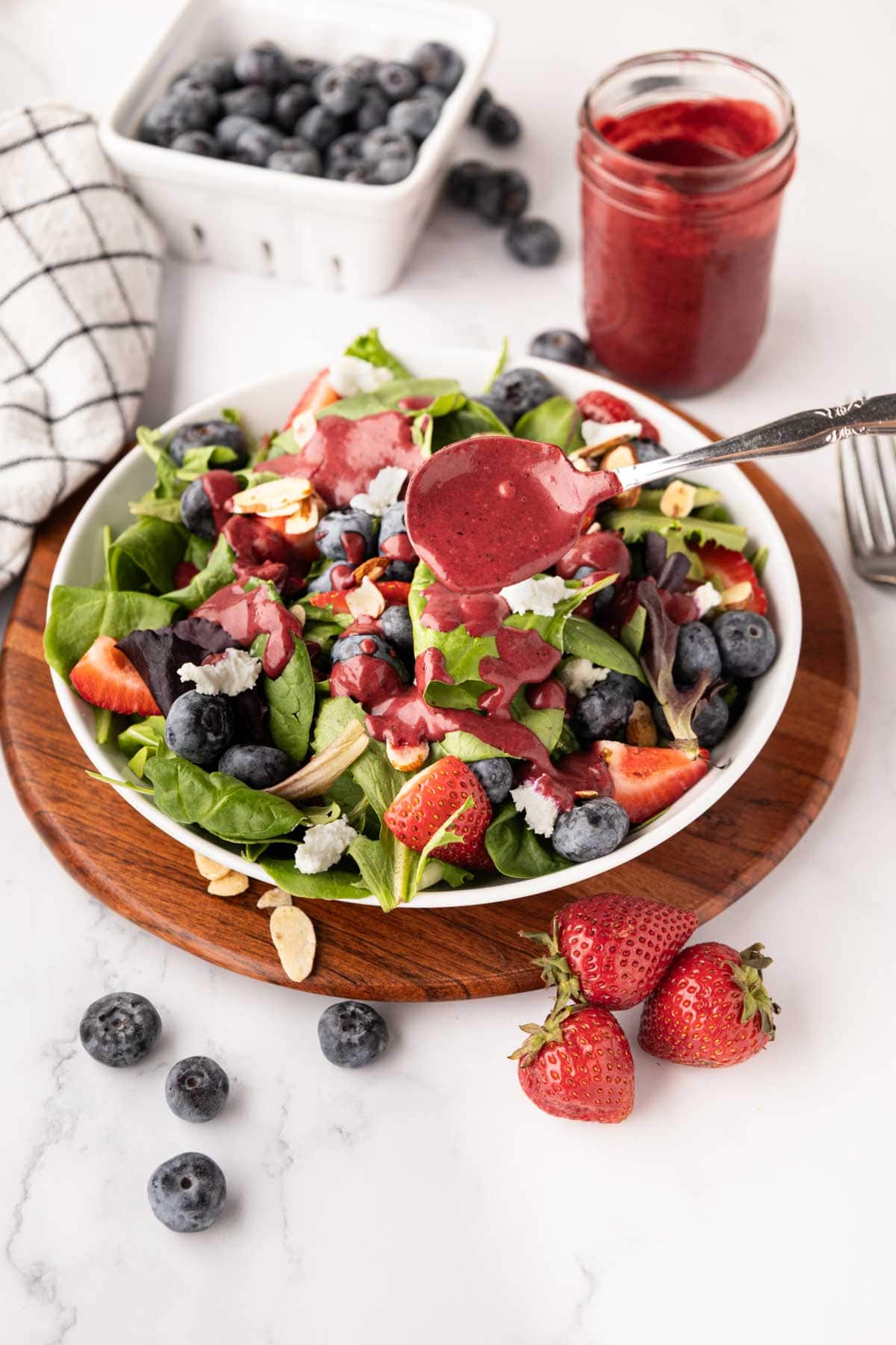 Spooning blueberry dressing on salad.