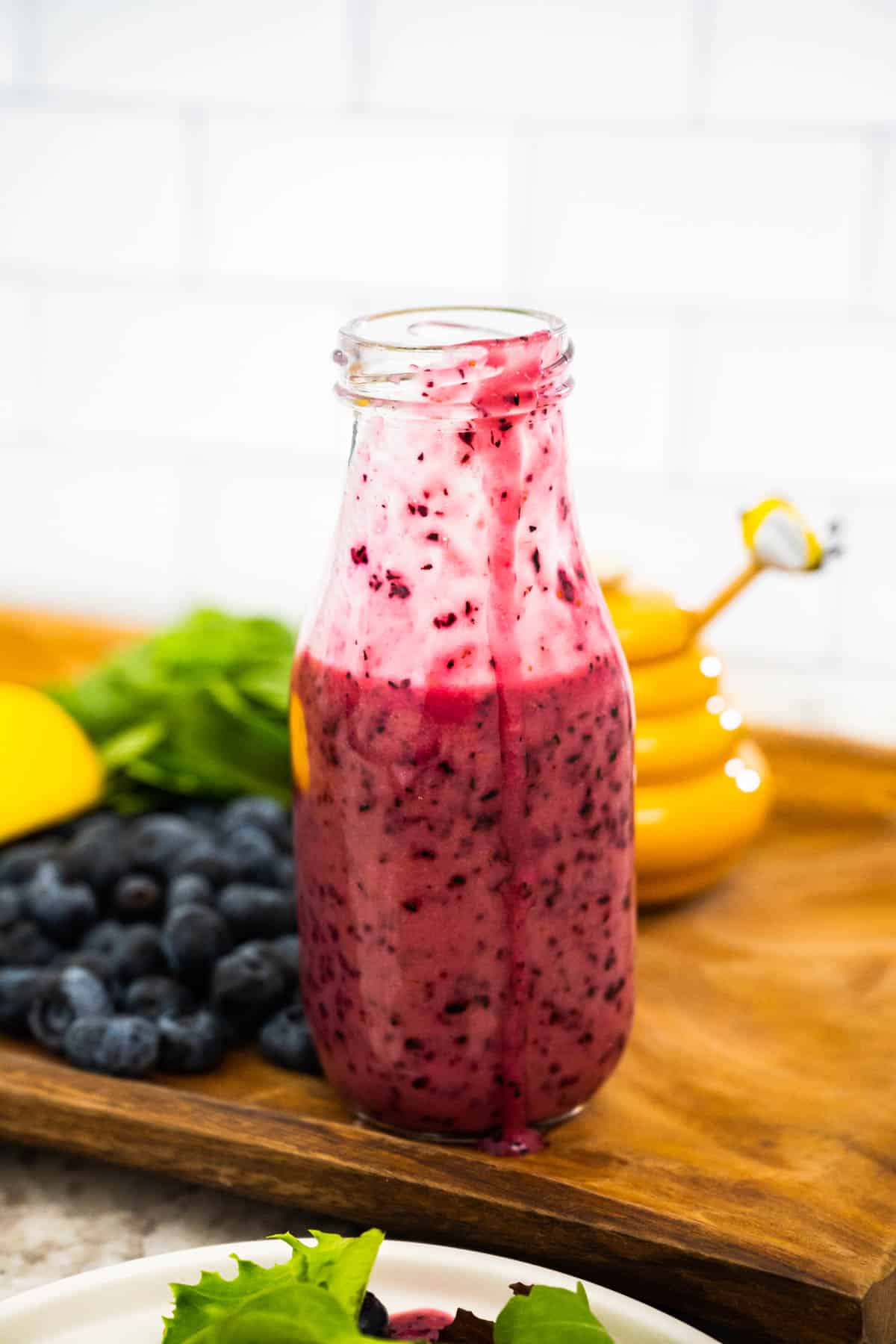 Upclose bottle of blueberry vinaigrette after being poured with dressing spilling down side of bottle.